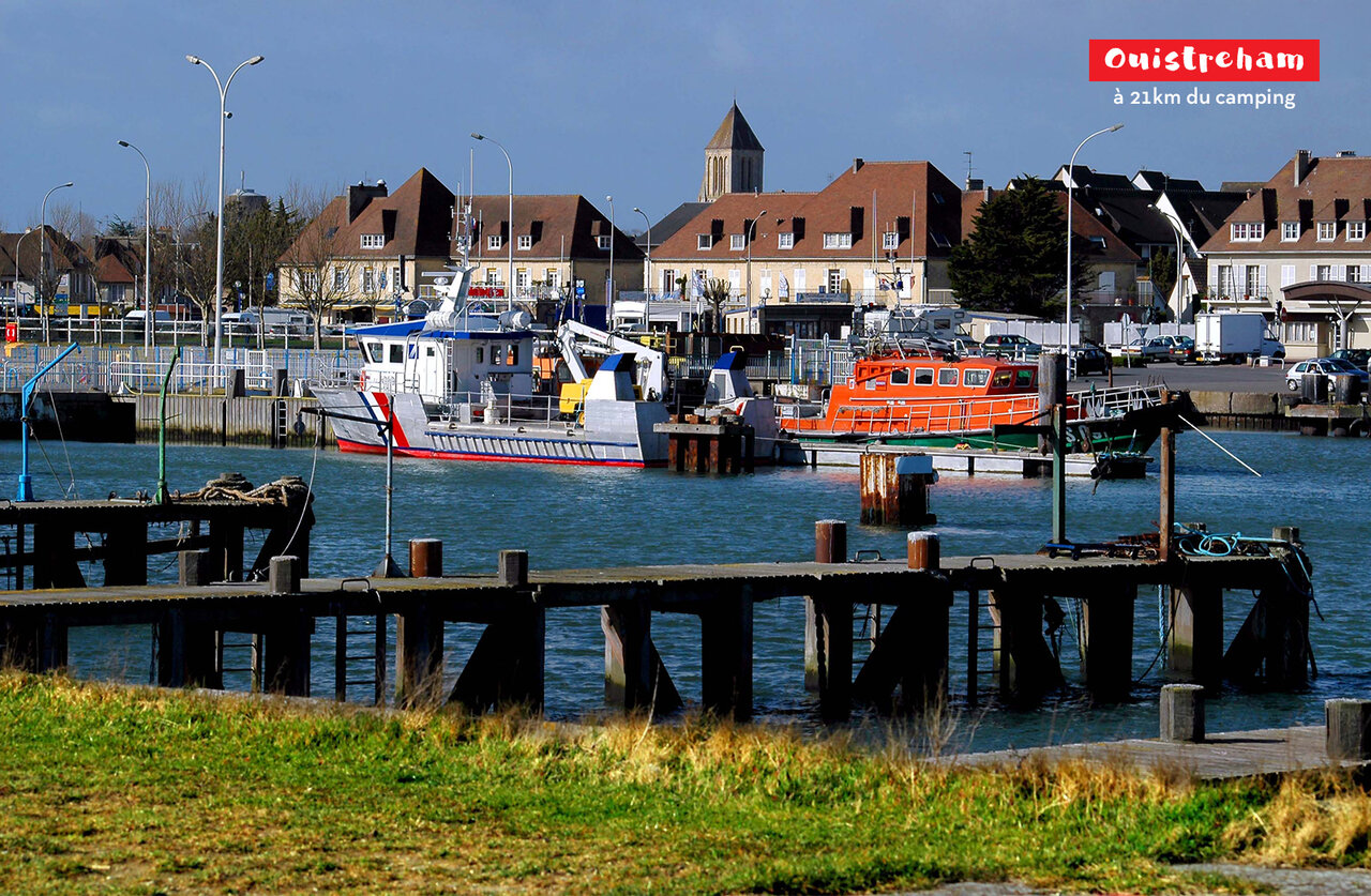 Port de Ouistreham avec bateaux, maisons et clocher d'�glise en Normandie.