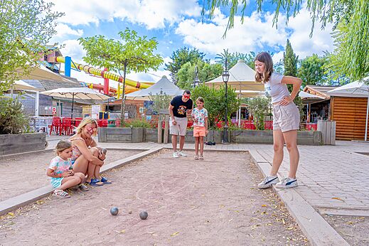 Famille jouant à la pétanque sur un terrain dédié au camping CAPFUN Donjon de Lars à Courseulles-sur-Mer (14).