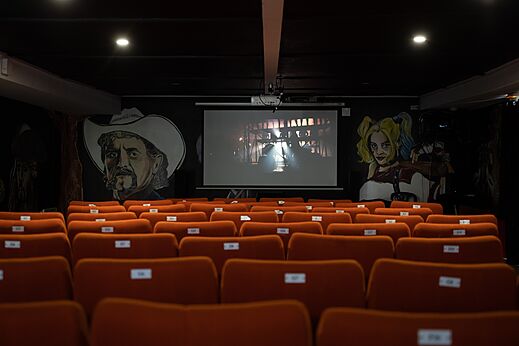 Salle de cinéma avec grand écran et sièges confortables au camping CAPFUN Dune Fleurie.