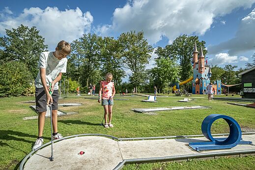 Enfants jouant au mini-golf avec château de jeux au camping CAPFUN Eibernest à Eibergen.