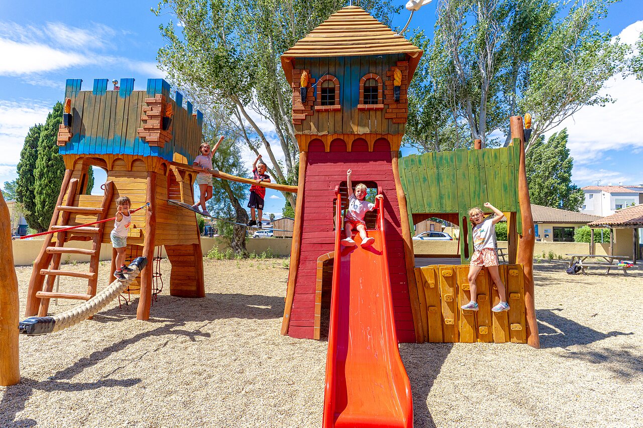 Aire de jeux en bois avec toboggan et enfants souriants au camping VAGUES OCEANES Elys�e � Le Grau du Roi (30).