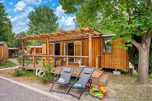 Mobil-home en bois avec terrasse couverte et chaises au camping CAPFUN El Moli � Elne (66).