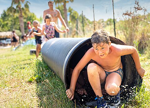 Enfant sortant d'un tunnel aquatique, jeu d'eau au camping CAPFUN El Moli � Elne (66).
