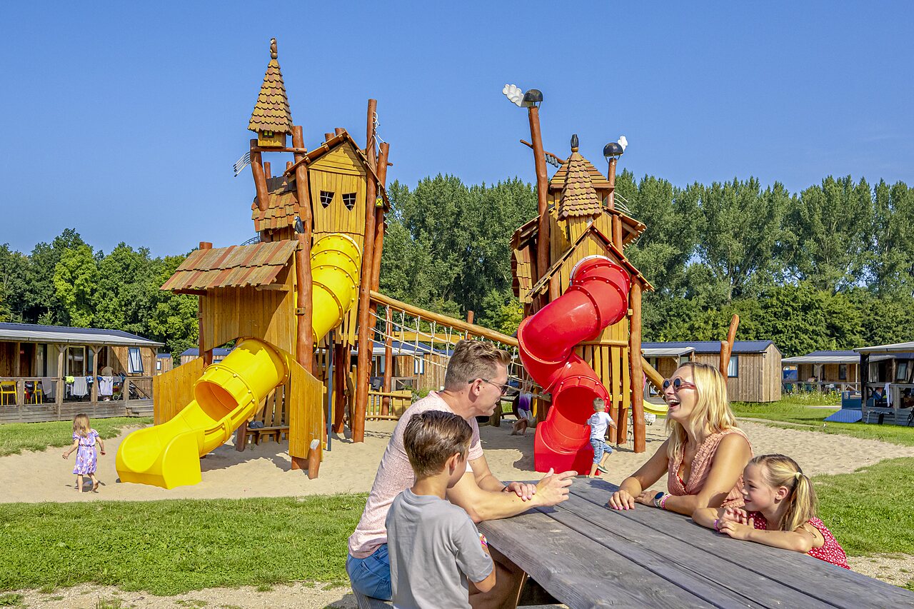 Aire de jeux avec toboggans et famille heureuse au camping CAPFUN Erkemederstrand � Zeewolde.