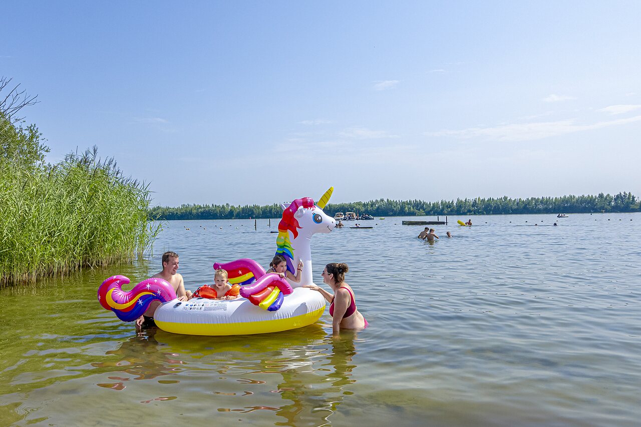 Famille jouant dans le lac avec licorne gonflable au camping CAPFUN Erkemederstrand � Zeewolde.