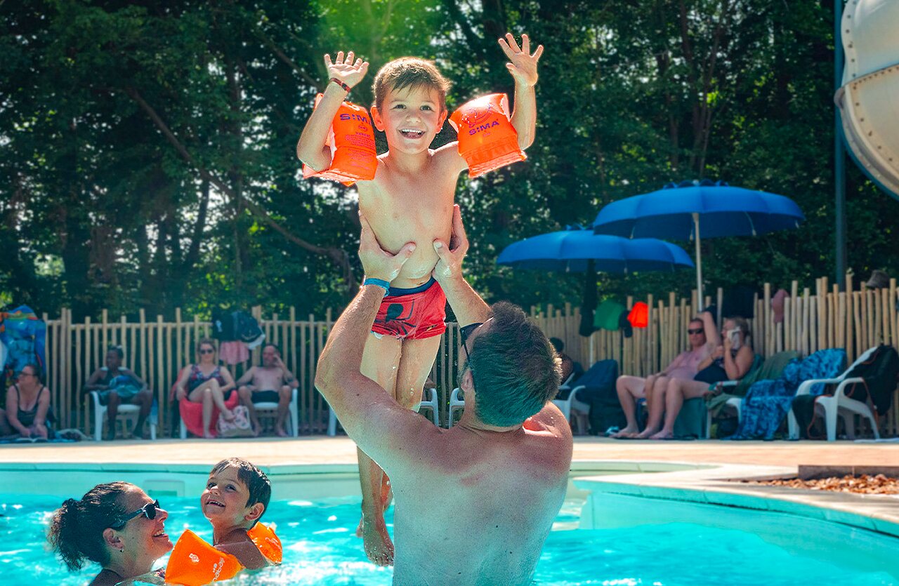 Famille s'amusant dans la piscine avec toboggan au camping VAGUES OCEANES Lac d'Erstein � Erstein (67).
