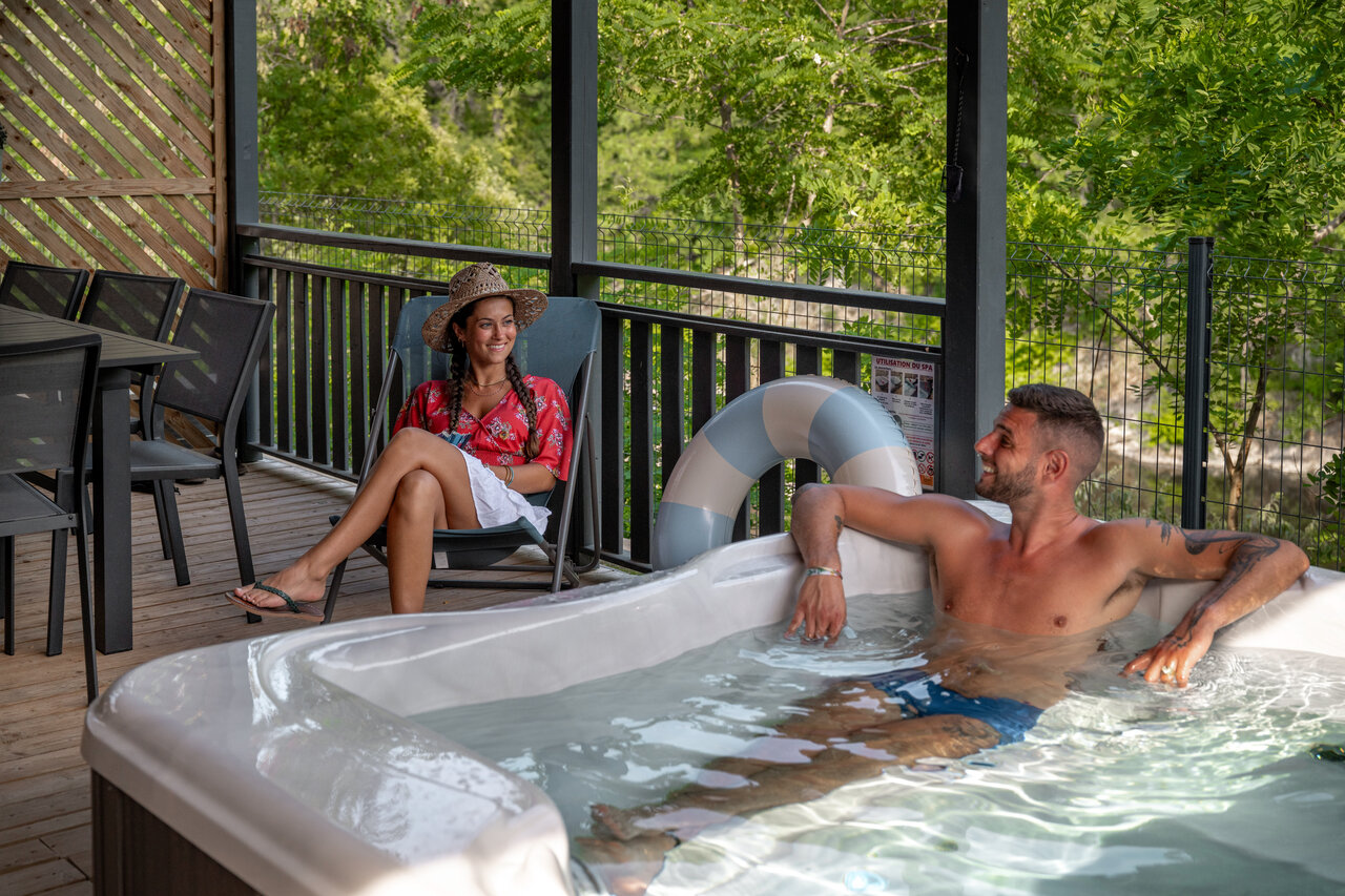 Couple profitant d'un spa priv� sur la terrasse au camping CLICOCHIC Eyrieux.