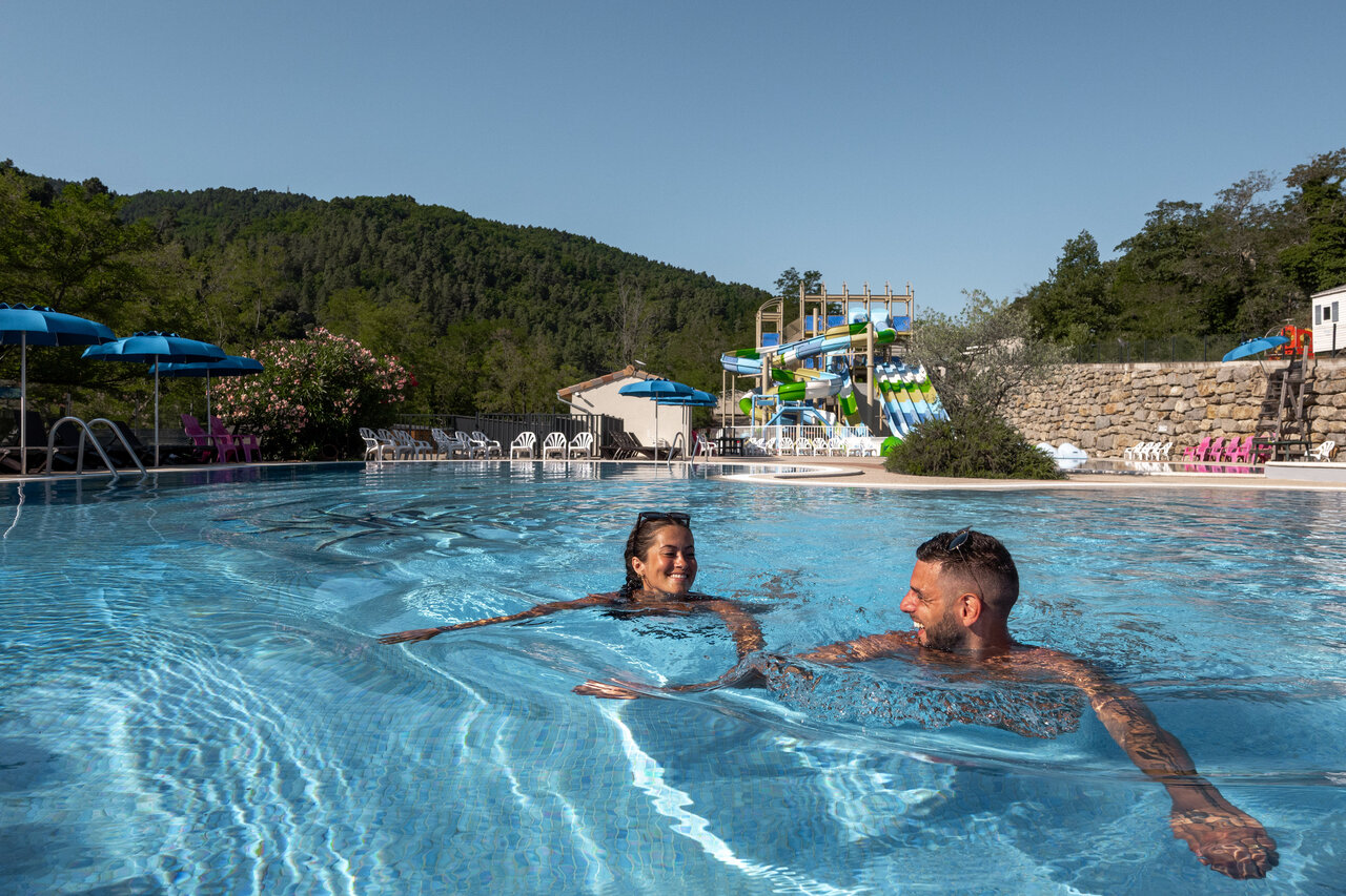 Piscine ext�rieure avec toboggans aquatiques et couple souriant au camping CLICOCHIC Eyrieux � Les OLLIERES-SUR-EYRIEUX.