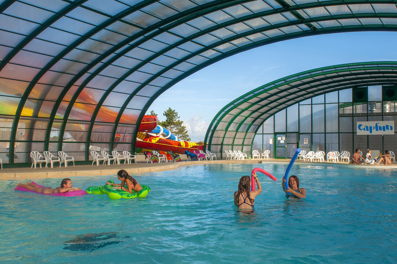 Piscine couverte avec toboggans et enfants jouant au camping CAPFUN Falaises � Gonneville sur Mer.