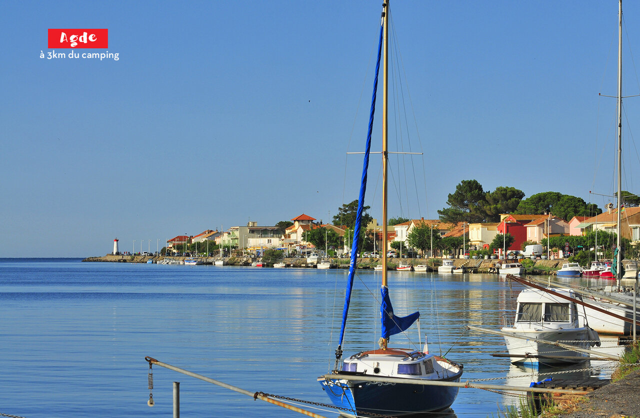 Port d'Agde avec bateaux, maisons color�es et phare, lieu � visiter pr�s du camping.