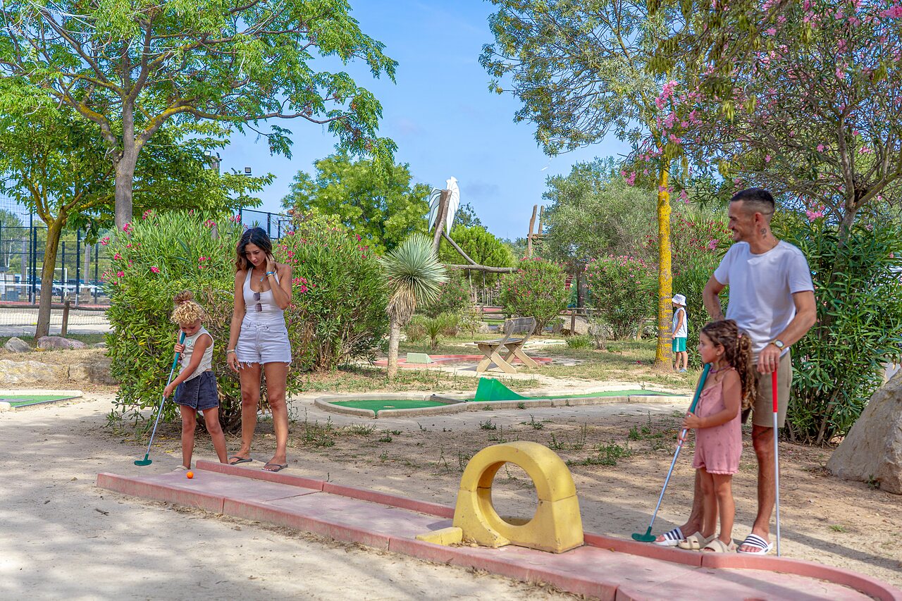 Famille jouant au mini-golf sur un parcours ext�rieur au camping CAPFUN Fleurs d'Agde � AGDE (34).