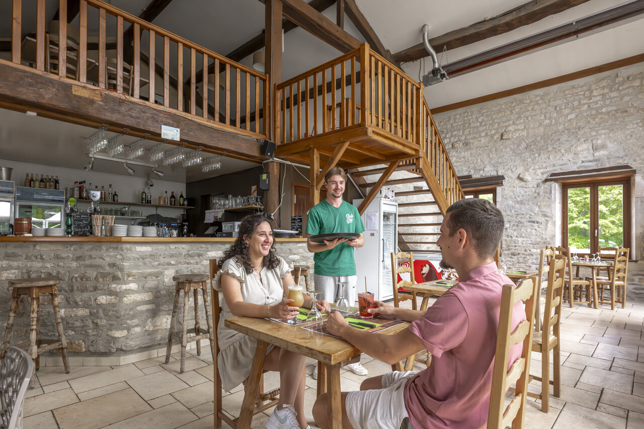 Int�rieur restaurant-bar avec couple et serveur au camping CLICOCHIC Forge Sainte Marie � Thonnance-les-Moulins.