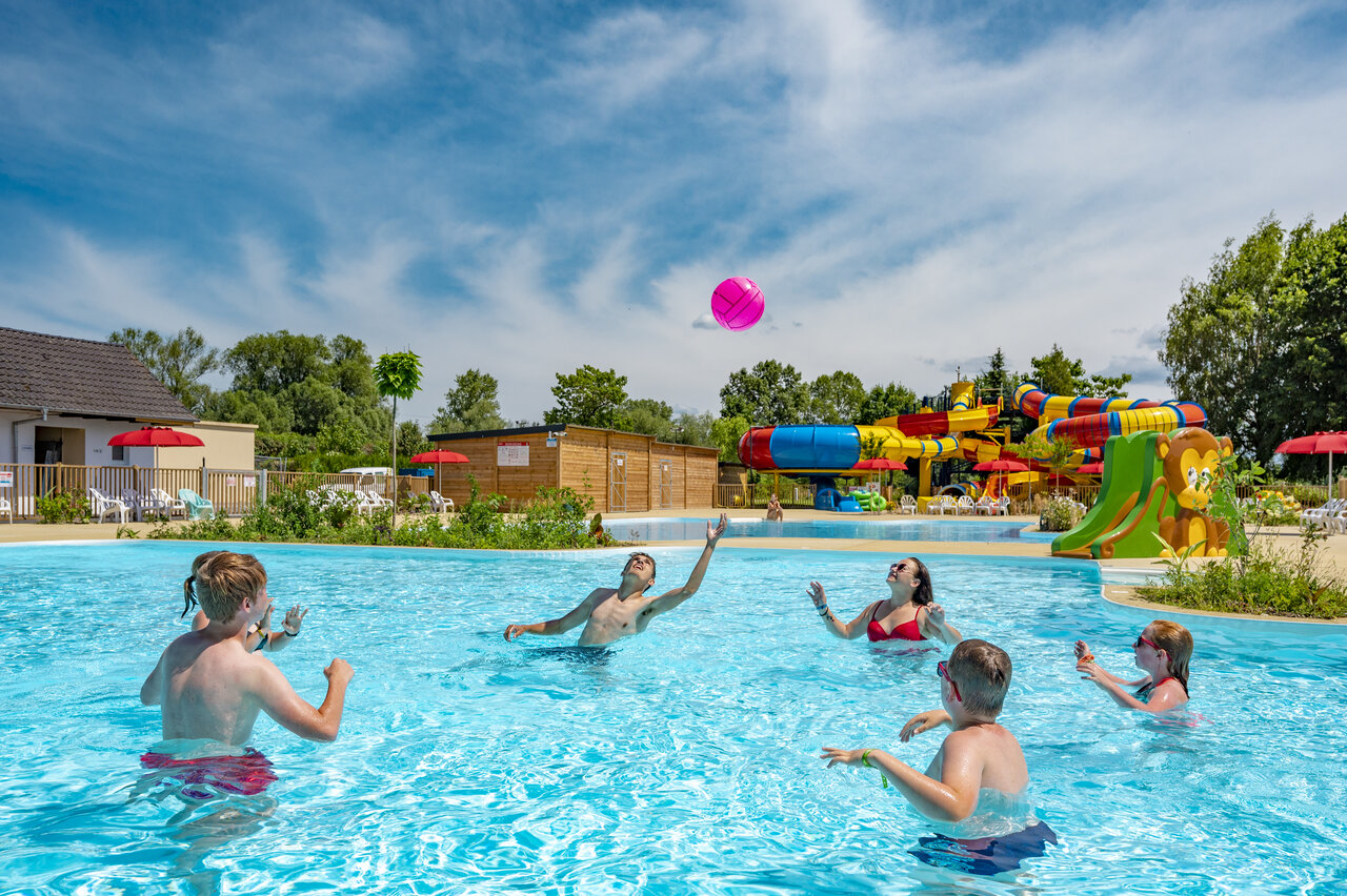 Famille jouant au ballon dans la piscine avec toboggans au camping CAPFUN Fort Falabraque � Seltz (67).