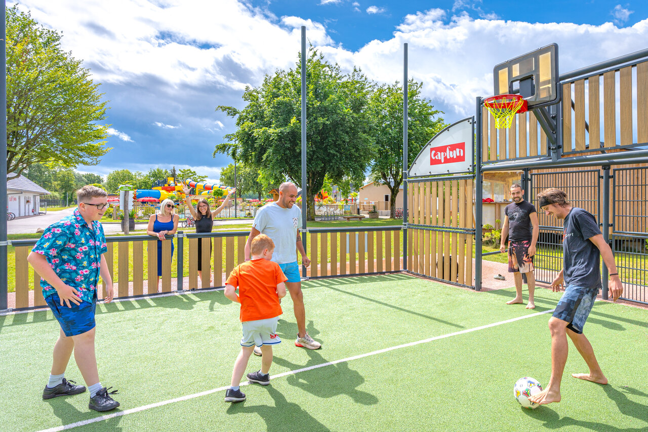 Terrain multisport avec famille jouant au football et basketball au camping CAPFUN Fort Falabraque � Seltz (67).