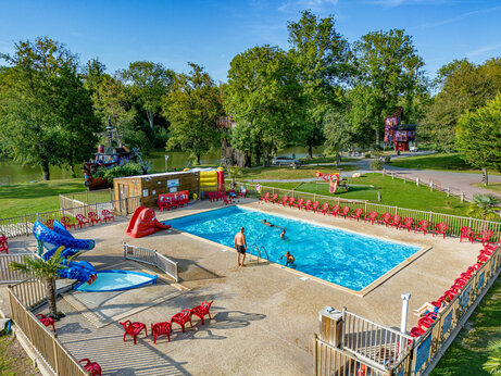 Piscine extérieure avec toboggans et chaises rouges au camping CAPFUN Fredland à Tournan en Brie (77).