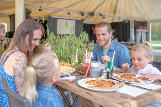 Famille souriante mangeant des pizzas au restaurant du camping CAPFUN Fredland à Tournan en Brie (77).