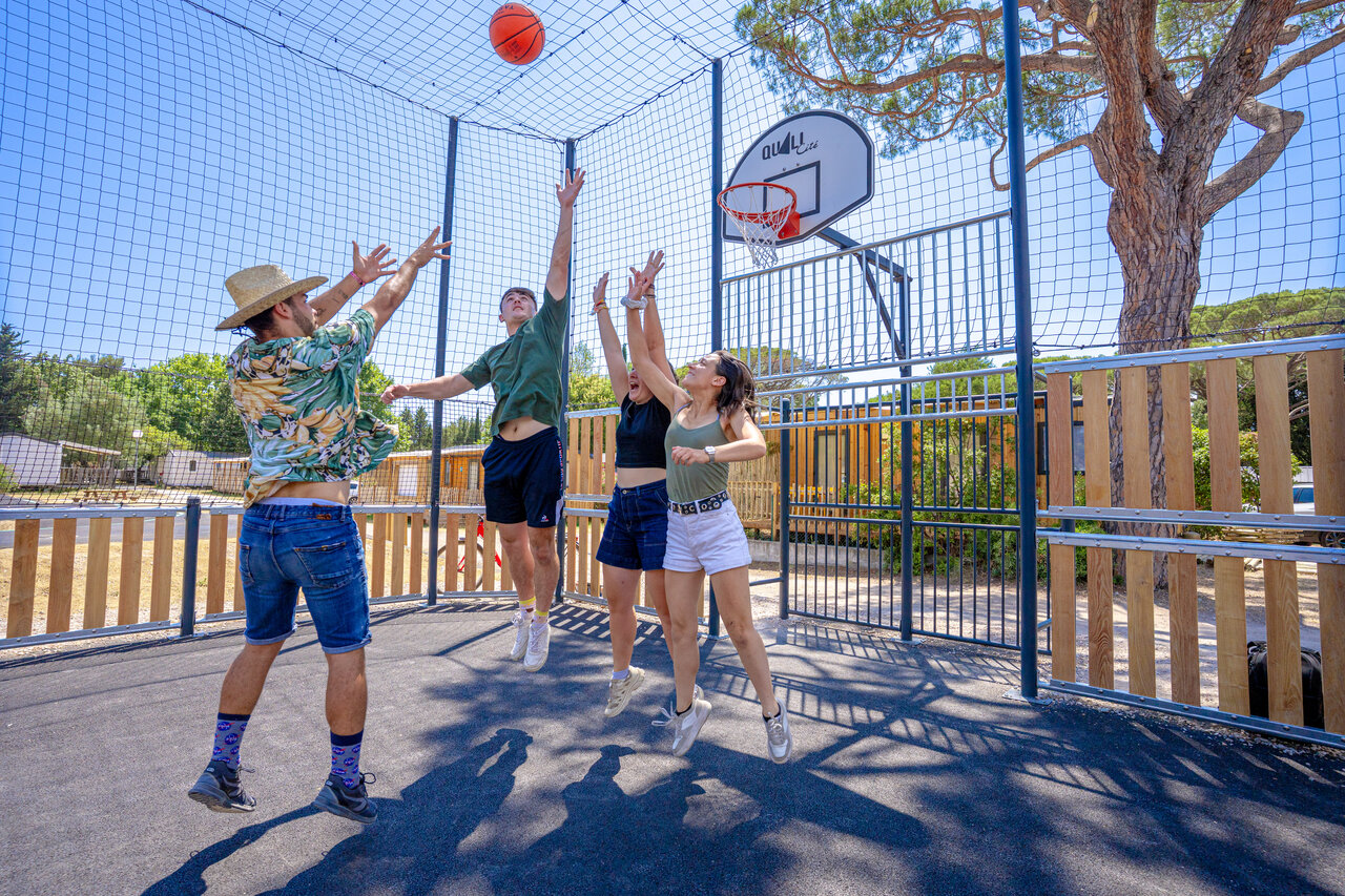 Jeunes jouant au basketball sur terrain multisport au camping CAPFUN Le Fr�jus � Fr�jus.
