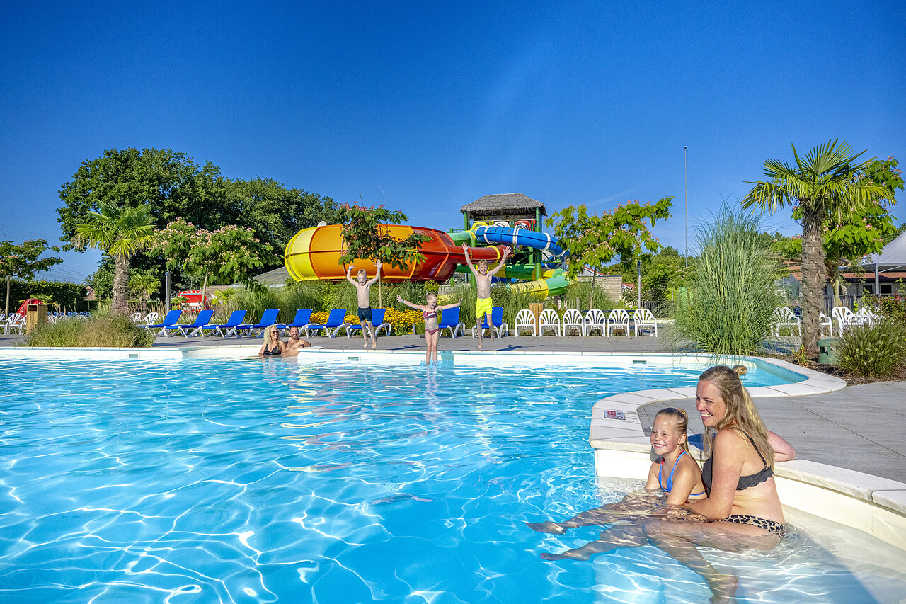 Piscine ext�rieure avec toboggans aquatiques et famille joyeuse au camping CAPFUN De Fruithof � Klijndijk.