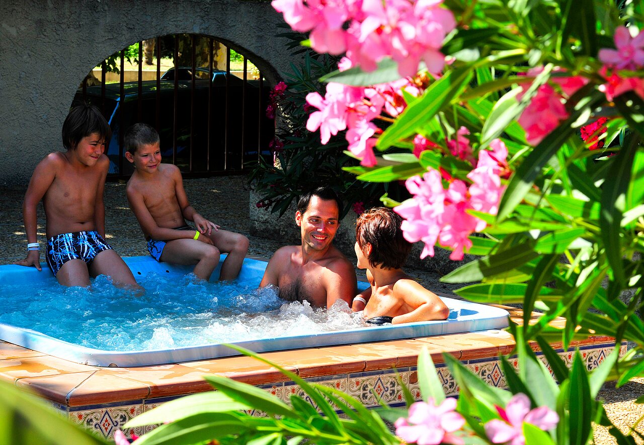 Famille souriante profitant du jacuzzi bouillonnant au camping CAPFUN Fumades � ALLEGRE-LES-FUMADES (30).