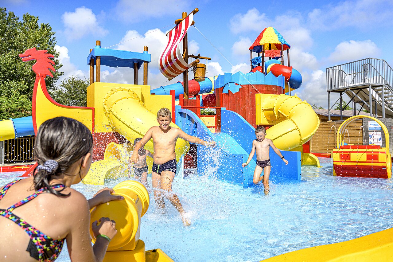 Parc aquatique avec toboggans, jeux d'eau et enfants rieurs au camping CAPFUN Golf � SAINT JEAN DE LA RIVIERE (50).