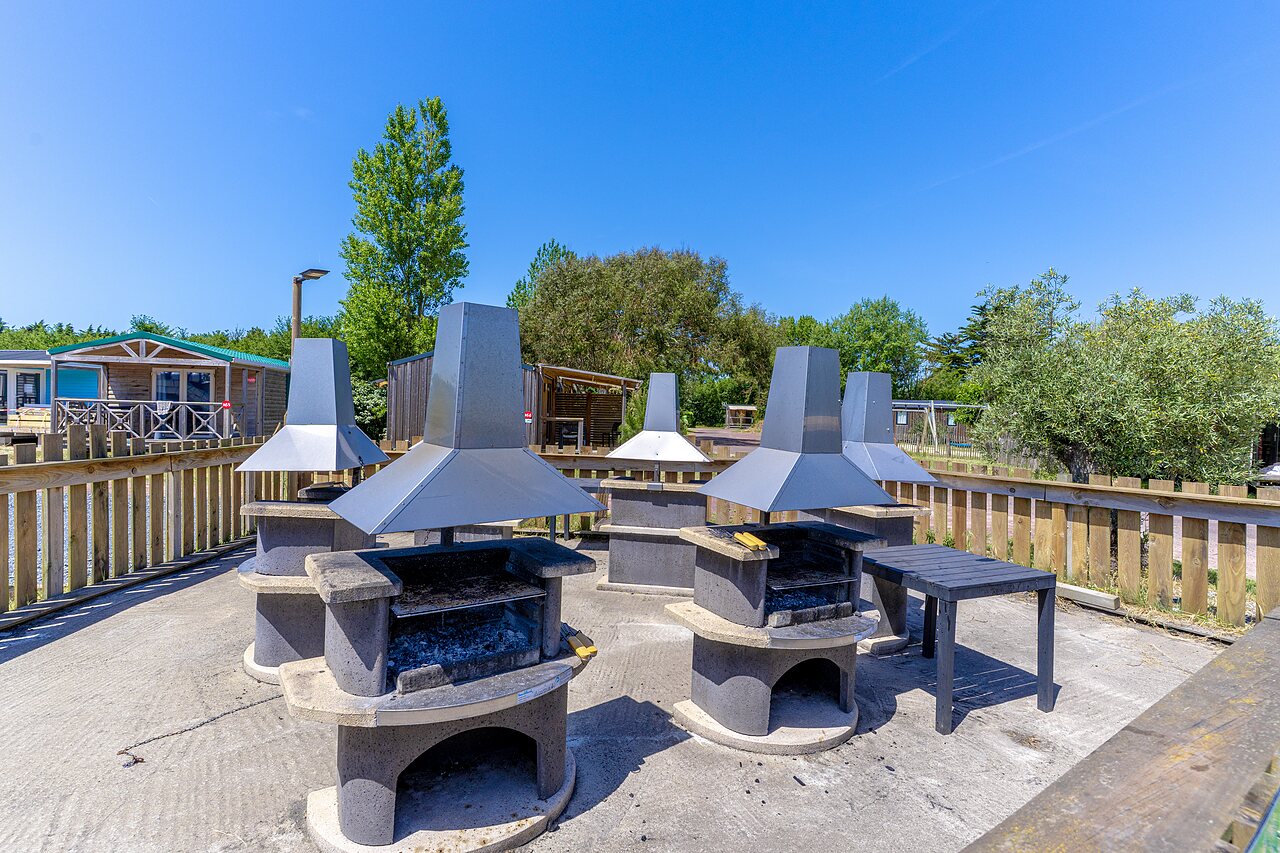 Espace barbecue commun avec plusieurs grills au camping CAPFUN Golf � SAINT JEAN DE LA RIVIERE (50).
