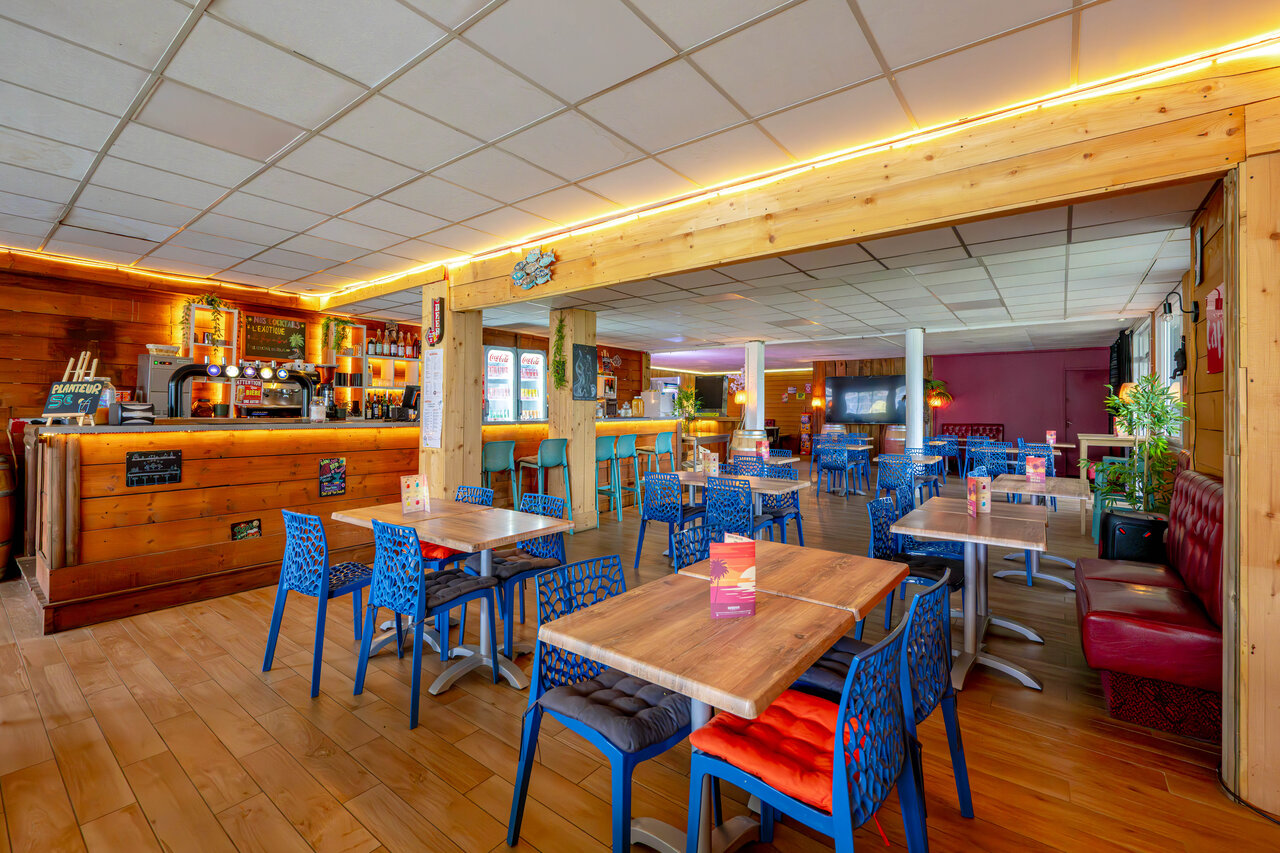 Bar et espace restaurant avec tables et chaises au camping CAPFUN Grand Large � FOUESNANT (29).