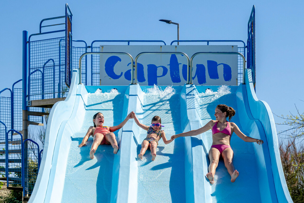 Enfants joyeux glissant sur toboggan aquatique multi-pistes au camping CAPFUN Grand Large � FOUESNANT (29).