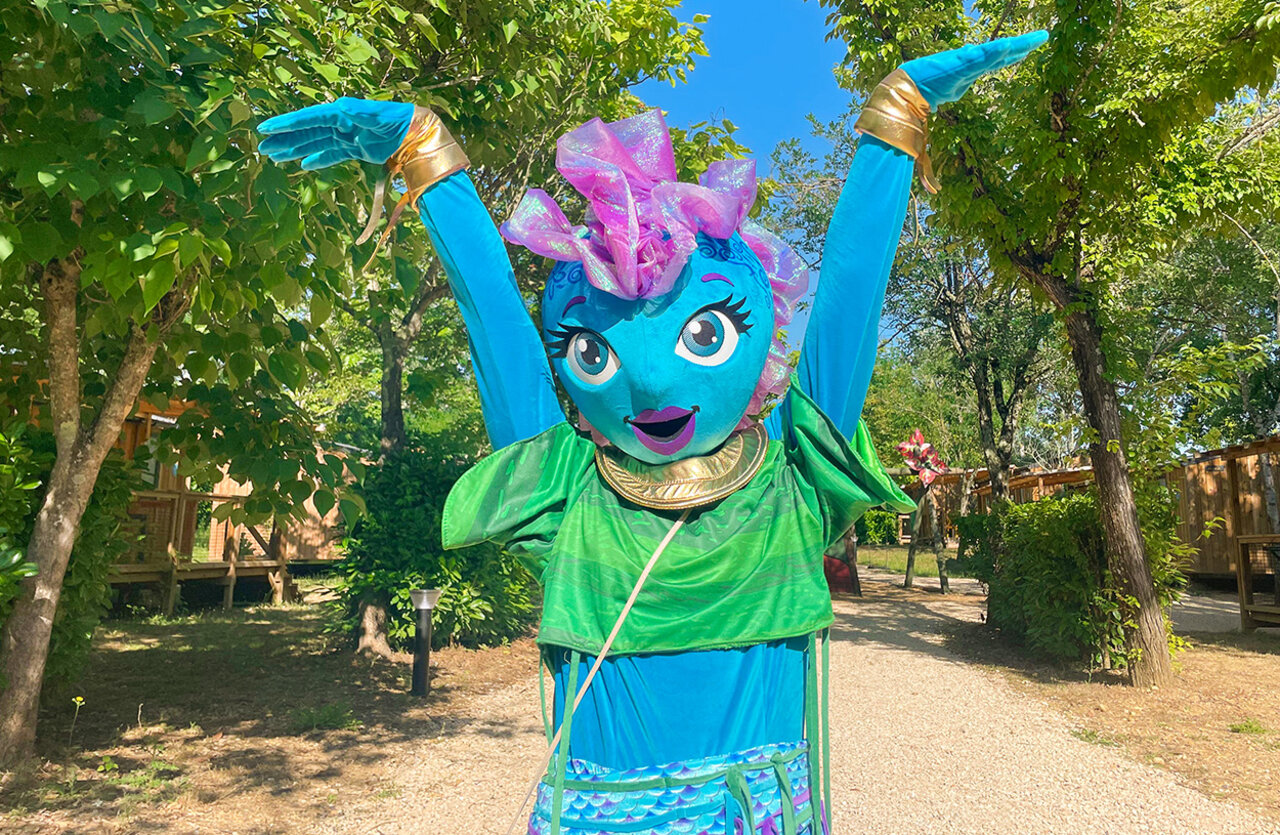 Mascotte bleue et verte souriante pour l'animation au camping VAGUES OCEANES Granges (24).
