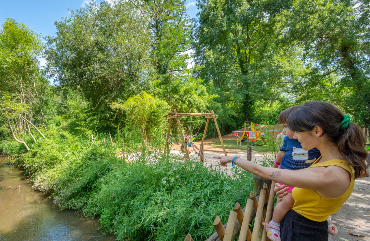 Aire de jeux avec balan�oires et enfants, bord de rivi�re au camping VAGUES OCEANES Granges � GROLEJAC (24).