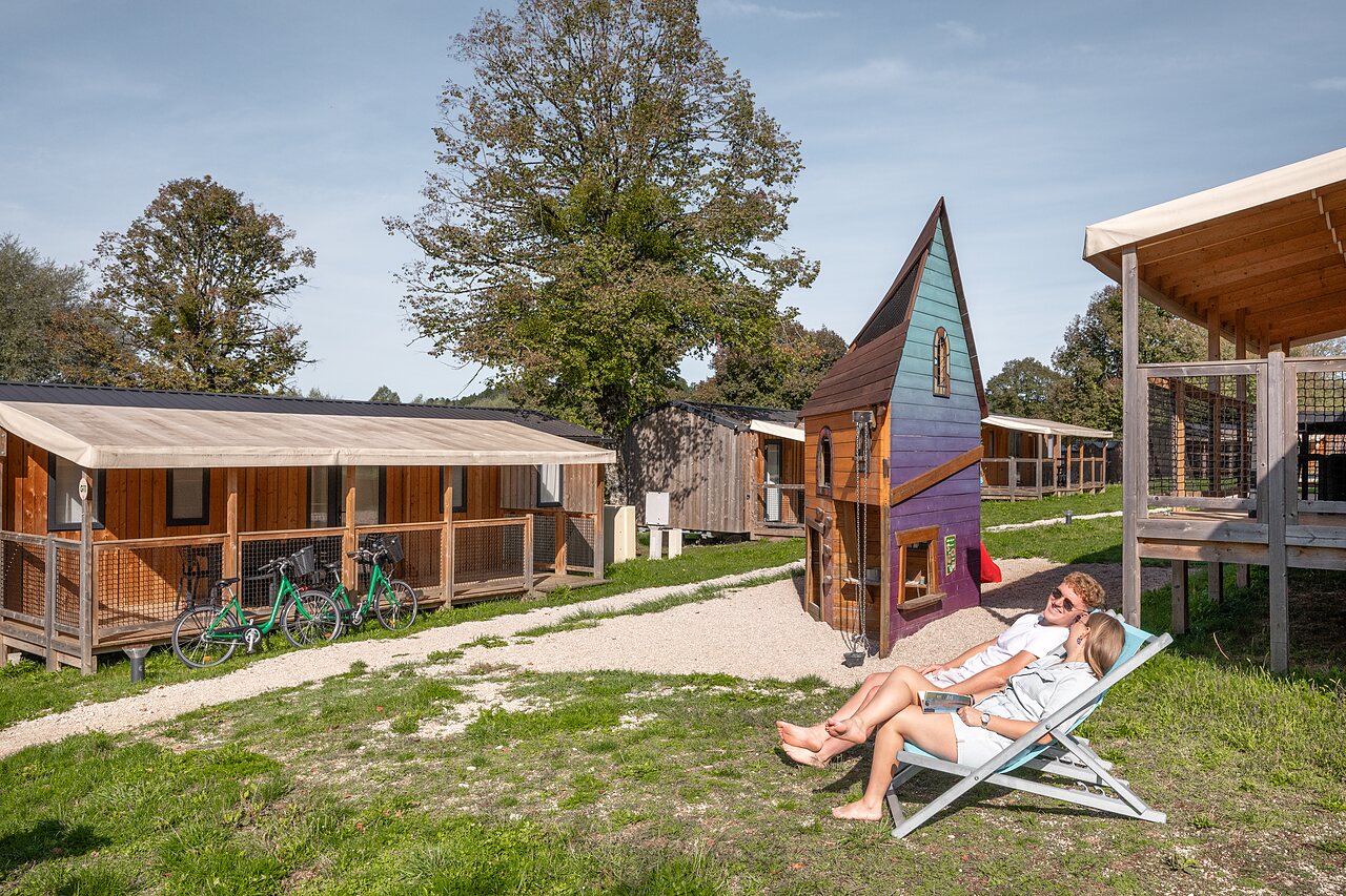 Couple relaxant pr�s d'un chalet et aire de jeux au camping CLICOCHIC Grisi�re � Clairvaux-les-Lacs (39).