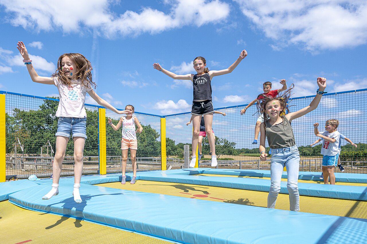 Enfants joyeux sautant sur les trampolines du parc de jeux au camping CLICOCHIC Grisi�re � Clairvaux-les-Lacs (39).