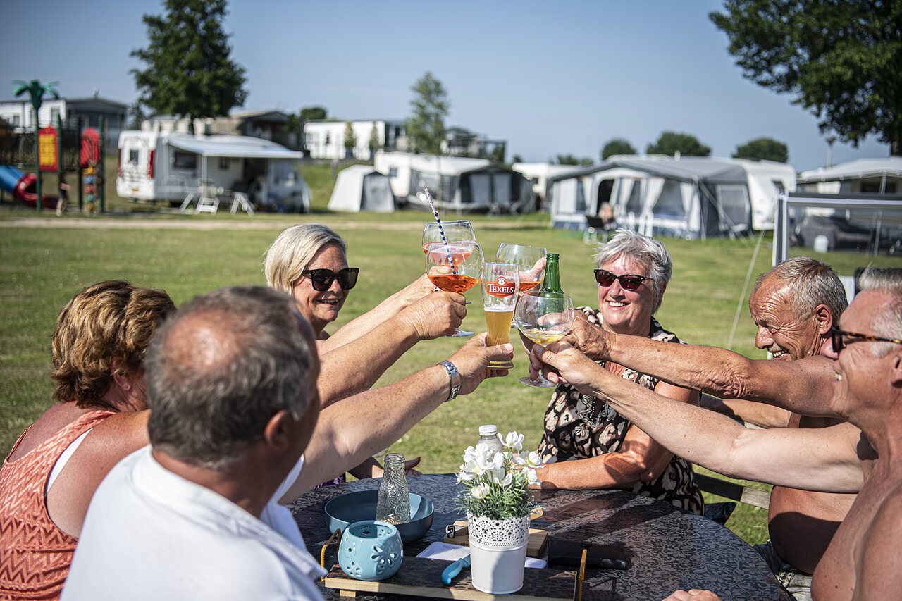 Amis seniors trinquant joyeusement sur un emplacement de camping au CAPFUN Groene Eiland.