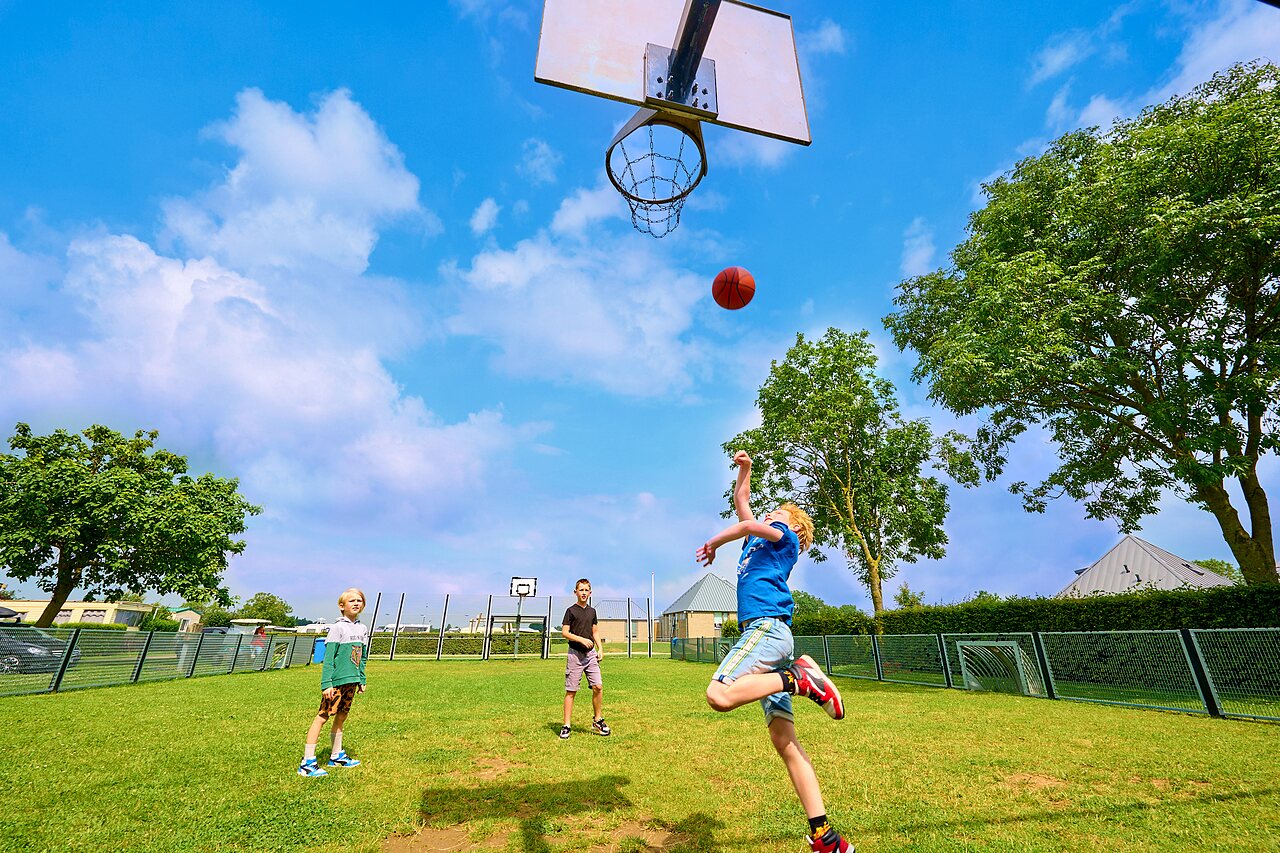Enfants jouant au basketball sur terrain multisport au camping CAPFUN Groene Eiland � Appeltern.