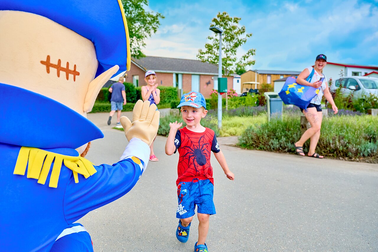 Mascotte saluant un enfant souriant lors d'une animation au camping CAPFUN Groene Eiland � Appeltern.