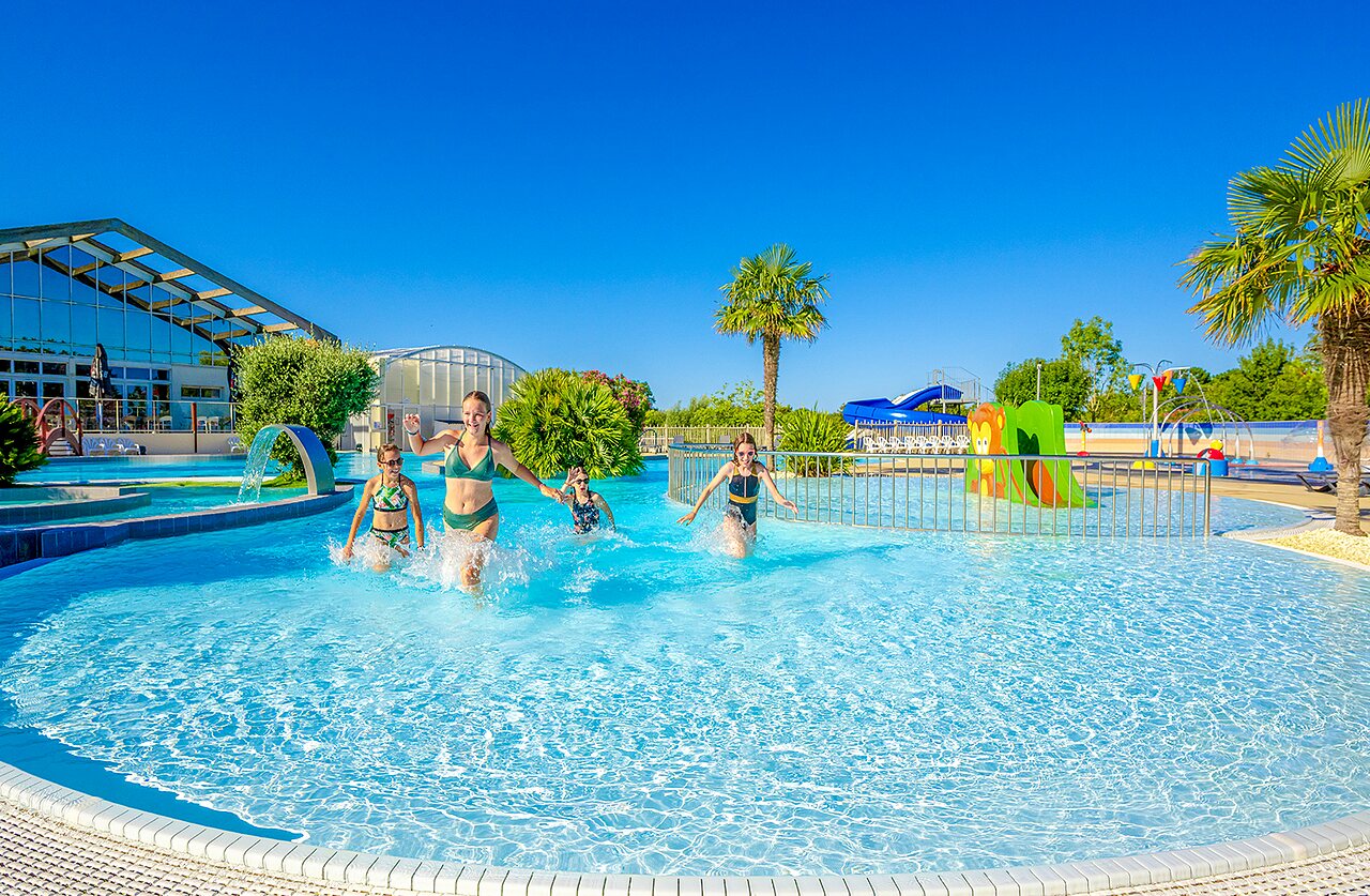 Enfants jouant dans la piscine ext�rieure avec toboggans au camping VAGUES OCEANES Grosses Pierres � Saint-Georges-d'Ol�ron (17).
