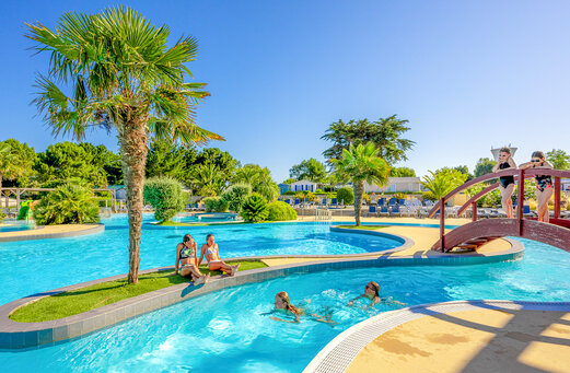 Piscine extérieure, rivière et pont au camping VAGUES OCEANES Grosses Pierres.