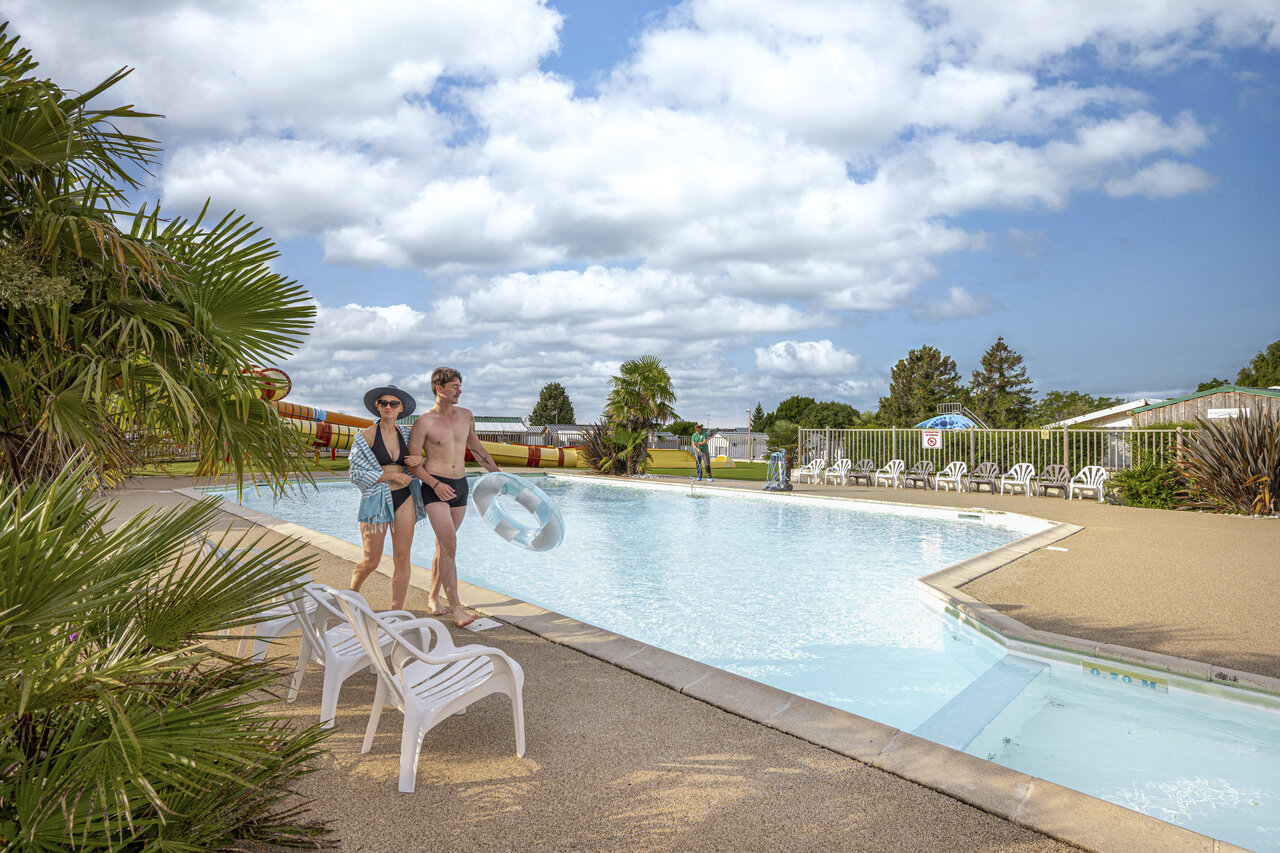 Couple � la piscine ext�rieure avec toboggans au camping CLICOCHIC Haras de Deauville.