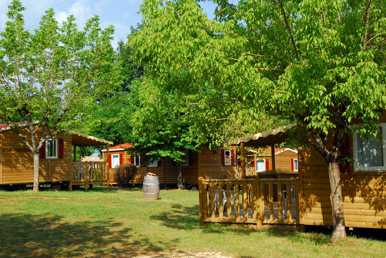 Chalets en bois, terrasses et arbres au camping CAPFUN Hauts de Ratebout � STE FOY DE BELVES (24).