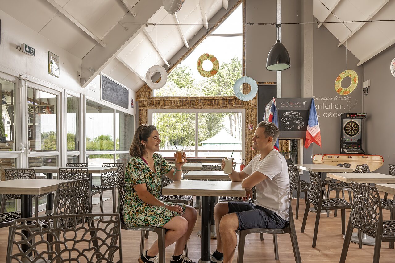 Couple souriant prenant un verre au bar du camping CLICOCHIC Havre de Berni�res.
