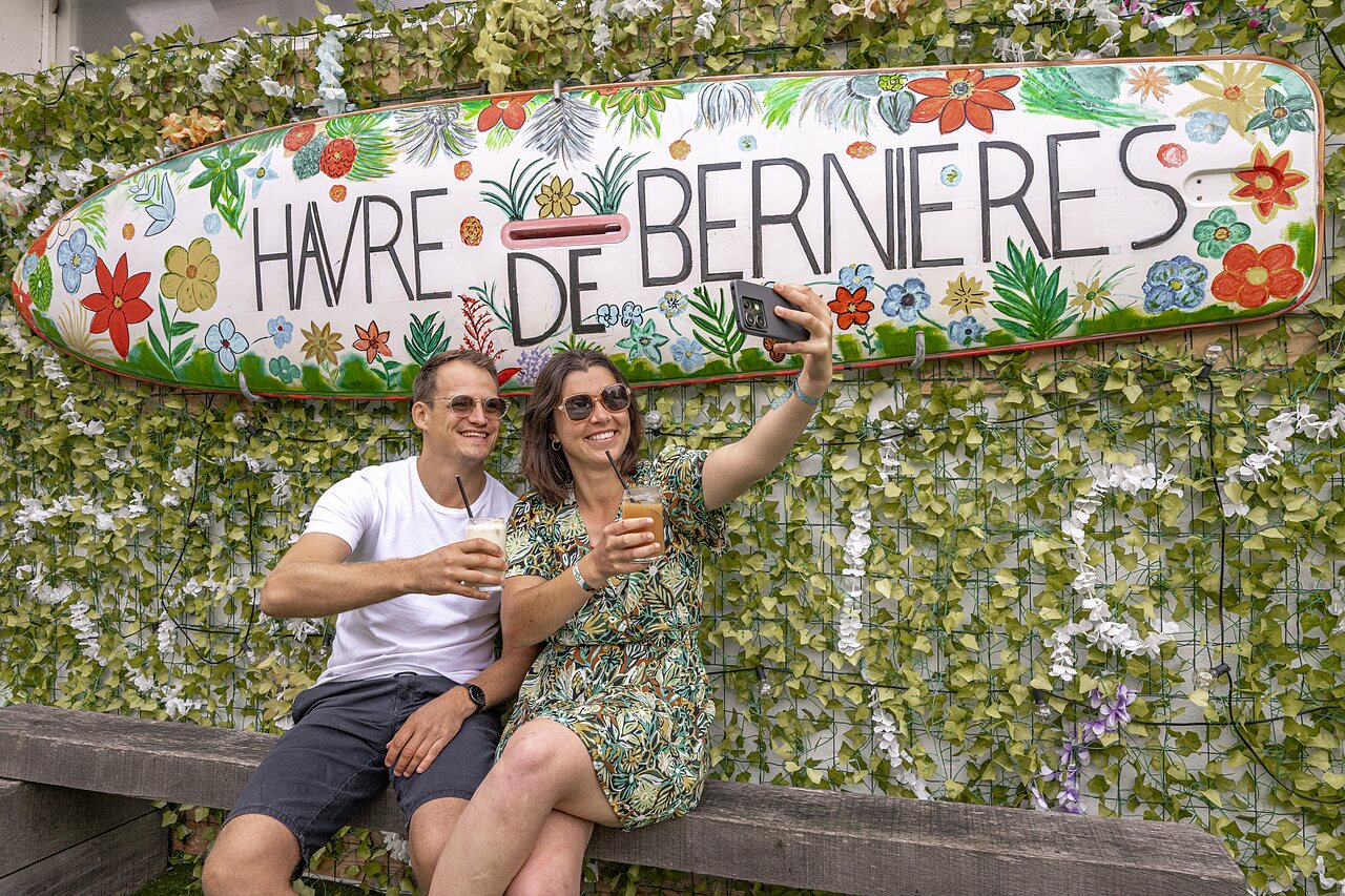 Couple souriant en selfie devant l'enseigne du camping CLICOCHIC Havre de Berni�res (14).