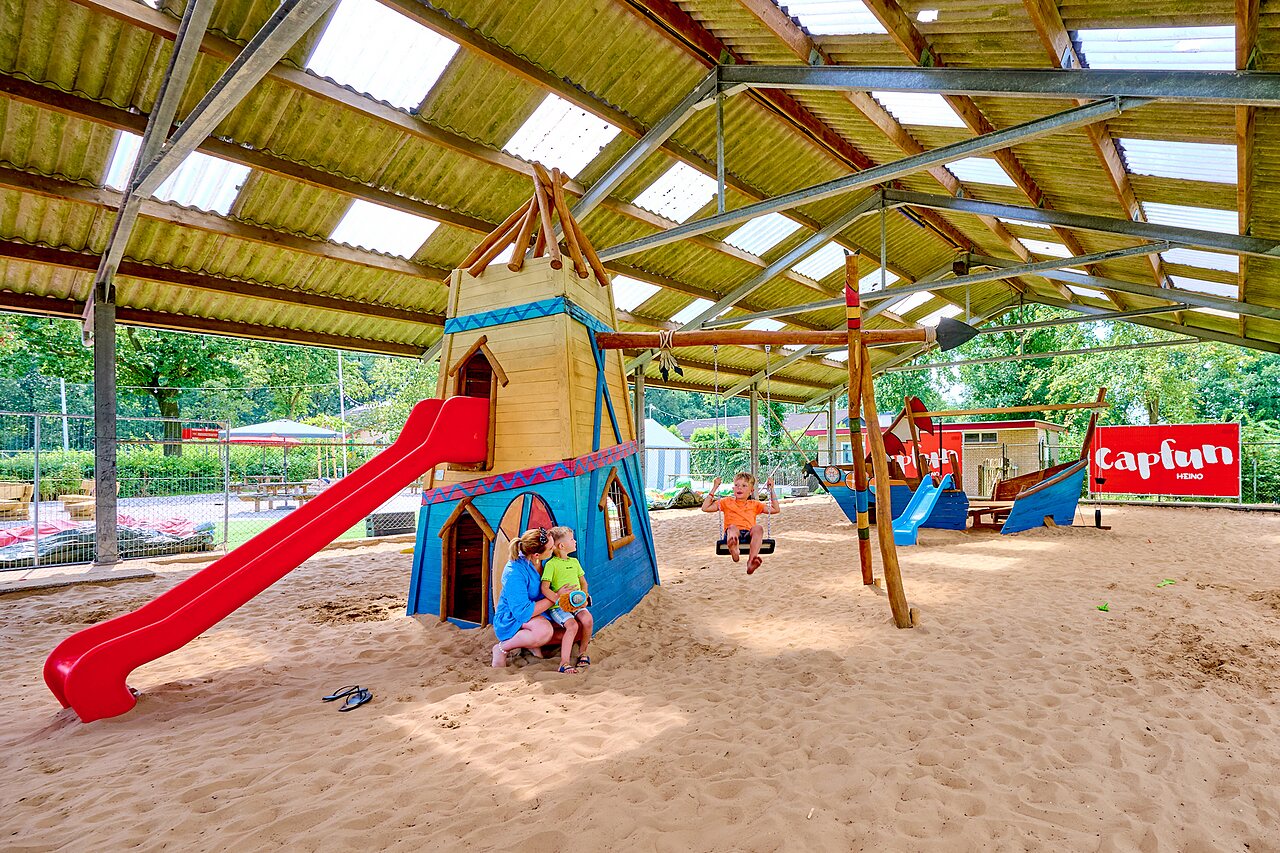 Aire de jeux couverte avec toboggan, balan�oires et sable au camping CAPFUN Heino � Heino.