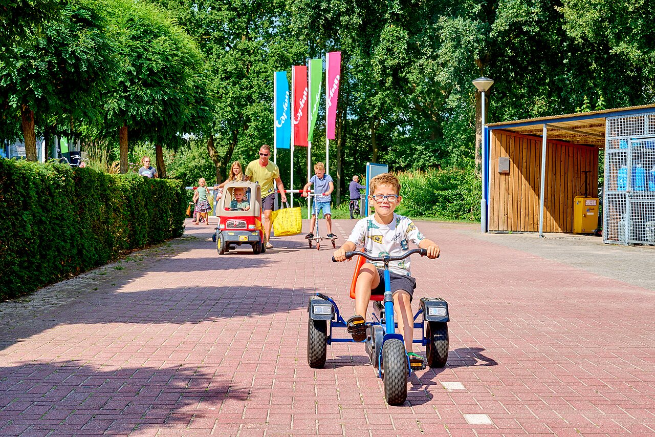 Enfants jouant avec kart � p�dales, trottinette et voiturette au camping CAPFUN Heino � Heino.