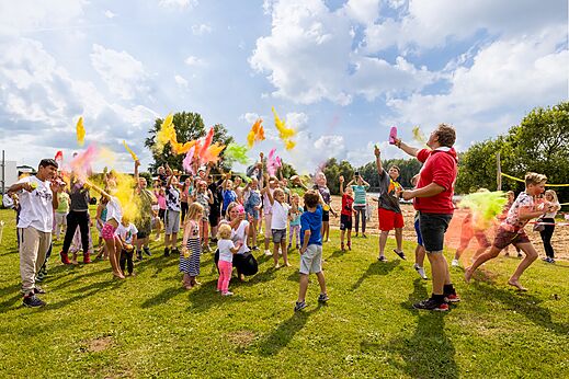 Enfants et adultes participant à une animation poudre colorée au camping CAPFUN IJsselstrand à Doesburg.