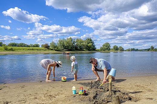 Famille construisant châteaux de sable sur plage, camping CAPFUN IJsselstrand Doesburg.