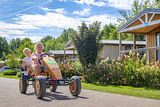 Enfants souriants sur un kart à pédales au camping CAPFUN IJsselstrand à Doesburg.