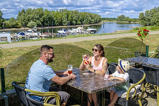Famille profitant de boissons à une table extérieure au camping CAPFUN IJsselstrand à Doesburg.