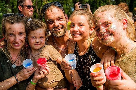 Famille souriante couverte de paillettes lors d'une animation au camping CAPFUN IJsselstrand.
