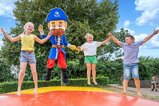 Enfants et mascotte pirate sautant sur coussin gonflable au camping CAPFUN IJsselstrand à Doesburg.