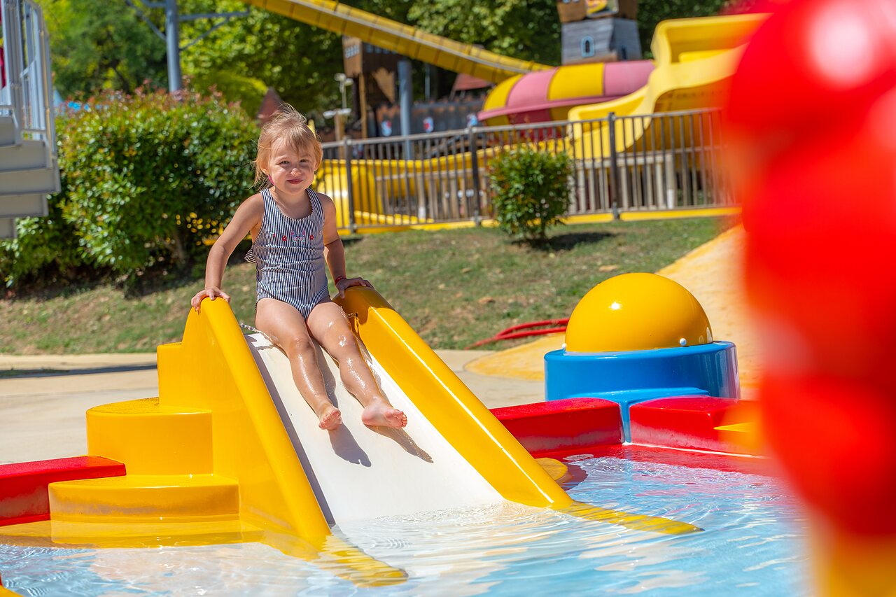 Petite fille souriante sur toboggan aquatique, pataugeoire au camping CAPFUN Imbours � LARNAS (07).