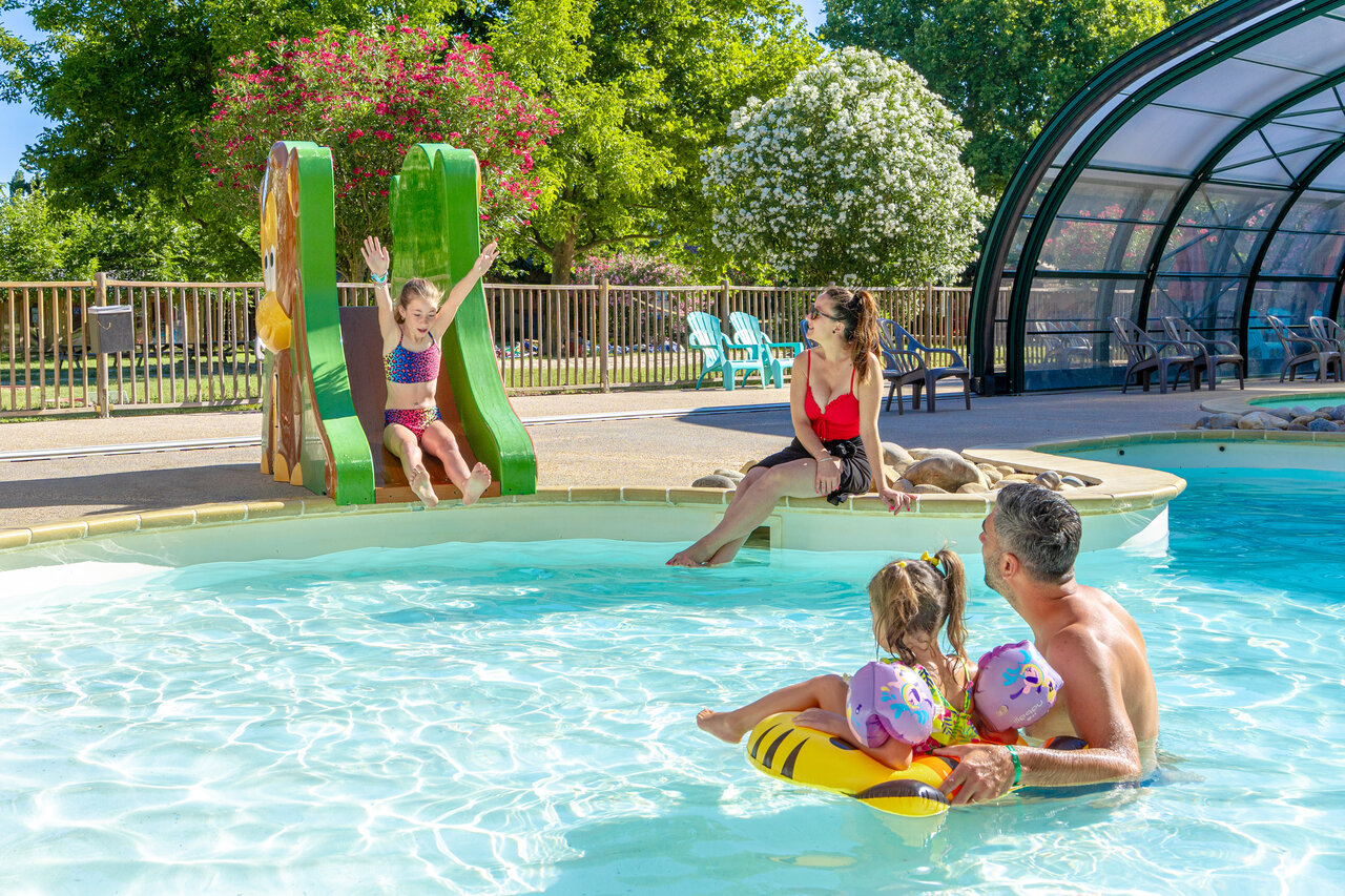 Enfant sur toboggan et famille profitant de la piscine au camping CAPFUN Jantou � LE THOR (84).